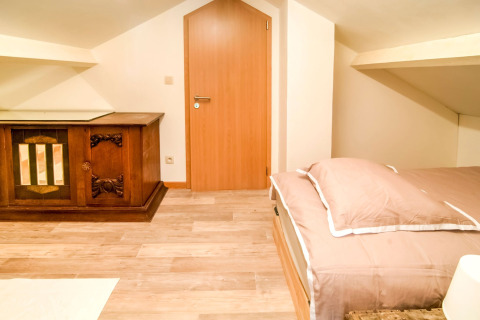 Bright attic room at Au Coeur du Pêcheur in Belgium with a double bed and vintage wooden cabinet.