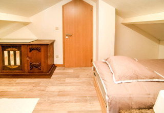 Bright attic room at Au Coeur du Pêcheur in Belgium with a double bed and vintage wooden cabinet.