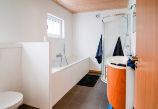 Modern bathroom with shower, bathtub, and wood ceiling at Au Coeur du Pêcheur lodge in Belgium.