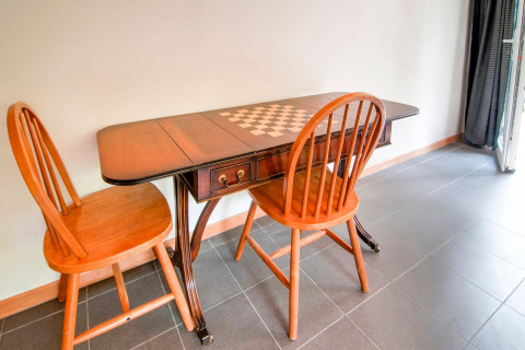 Wooden table with chessboard design and two wooden chairs, photo taken at Au Coeur du Pêcheur in Belgium.