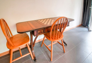 Wooden table with chessboard design and two wooden chairs, photo taken at Au Coeur du Pêcheur in Belgium.