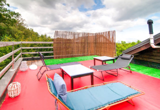 Rooftop terrace at Au Coeur du Pêcheur lodge in Belgium with loungers, small tables, and forest view.