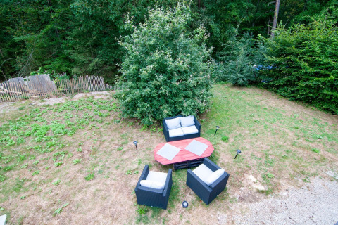 Outdoor seating area at a Belgian lodge, with garden furniture and greenery in a natural setting.