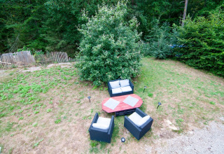 Outdoor seating area at a Belgian lodge, with garden furniture and greenery in a natural setting.