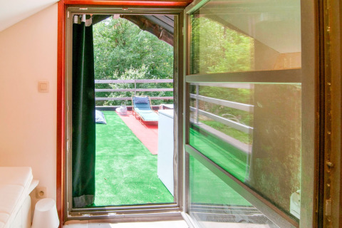 View from a room to a terrace with artificial grass and loungers at Au Coeur du Pêcheur lodge, Belgium.