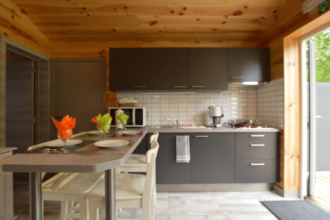 Moderne Küche in Le Chalet Chaleureux B, Belgien, mit Holzverkleidung, grauen Schränken und Bartisch.