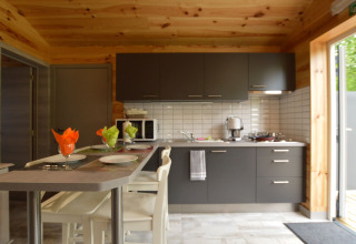 Moderne Küche in Le Chalet Chaleureux B, Belgien, mit Holzverkleidung, grauen Schränken und Bartisch.