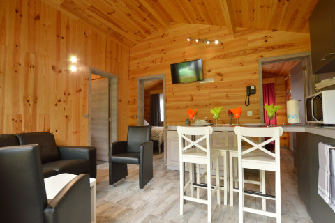 Gemütliche Lodge 'Le Chalet Chaleureux B' in Belgien mit Holzwänden, Sitzbereich und Küche.