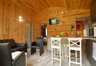 Gemütliche Lodge 'Le Chalet Chaleureux B' in Belgien mit Holzwänden, Sitzbereich und Küche.