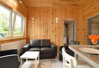 Wohnbereich in Le Chalet Chaleureux B in Belgien mit Holzverkleidung, Ledersesseln und Essbereich.