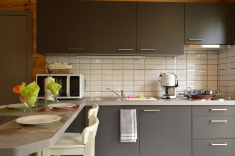 Moderne Küche in Le Chalet Chaleureux B, Belgien, mit grauen Schränken, Kaffeemaschine und Esstisch.