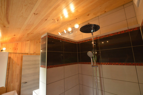 Moderne Duschkabine mit Holzdecke und Fliesen in einem Badezimmer von Le Chalet Chaleureux B in Belgien.