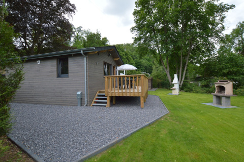Außenaufnahme der Le Chalet Chaleureux B-Lodge in Belgien mit Terrasse, Garten und Grillbereich.