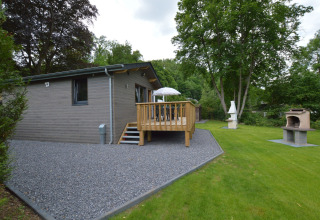 Außenaufnahme der Le Chalet Chaleureux B-Lodge in Belgien mit Terrasse, Garten und Grillbereich.
