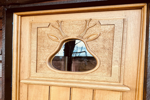 Houten deur met uitgesneden hertenmotief en raam, foto genomen bij chalet 'La Cabane' in België.