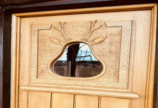 Houten deur met uitgesneden hertenmotief en raam, foto genomen bij chalet 'La Cabane' in België.
