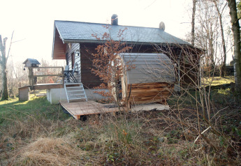 Udendørs billede af chalet 'La Cabane' i Belgien med træterrasse, have og omkringliggende natur.