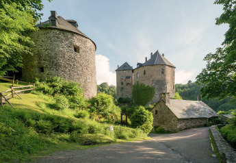 Smuk udsigt over stenkonstruktioner og frodige grønne omgivelser ved La Cabane chalet i Belgien.