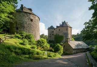 Uitzicht op stenen gebouwen en weelderig groen bij chalet La Cabane in België op een zonnige dag.