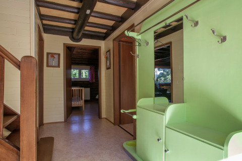 Eingangsbereich im Chalet 'Les Muguets' in Belgien, mit grüner Garderobe, Spiegel und Holztreppe.