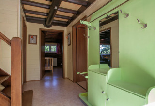 Eingangsbereich im Chalet 'Les Muguets' in Belgien, mit grüner Garderobe, Spiegel und Holztreppe.