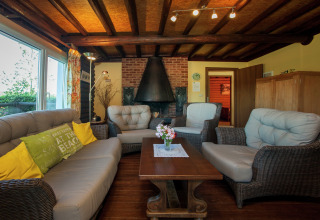 Gemütliches Chalet 'Les Muguets' in Belgien mit Holzbalkendecke, Kamin, Rattanmöbeln und Sofas.