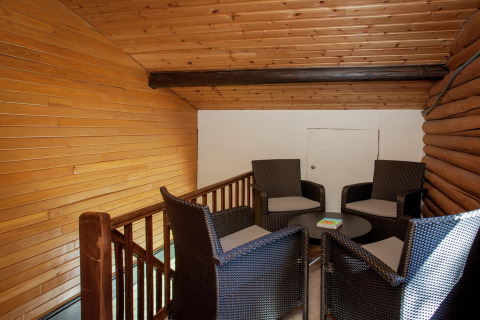 Gemütliche Sitzecke mit vier Korbstühlen und kleinem Tisch auf dem Dachboden eines Holzchalets.