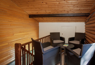 Gemütliche Sitzecke mit vier Korbstühlen und kleinem Tisch auf dem Dachboden eines Holzchalets.