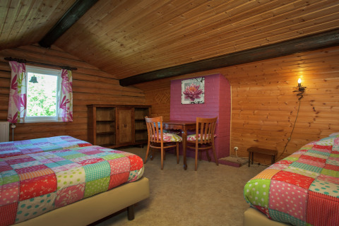 Gemütliches Schlafzimmer im Chalet Les Muguets, Belgien, mit Holzdecke, zwei Betten und bunter Einrichtung.