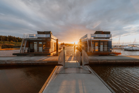 Husbåd ved Bärwalder See under en smuk solnedgang, fortøjet ved en havn med rolige omgivelser.