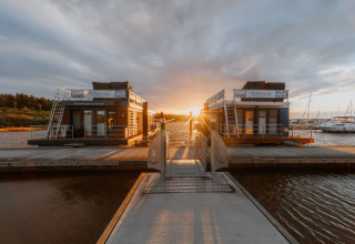 Husbåd ved Bärwalder See under en smuk solnedgang, fortøjet ved en havn med rolige omgivelser.