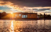 Atardecer en Houseboat am Bärwalder See, con una casa flotante moderna sobre las tranquilas aguas.