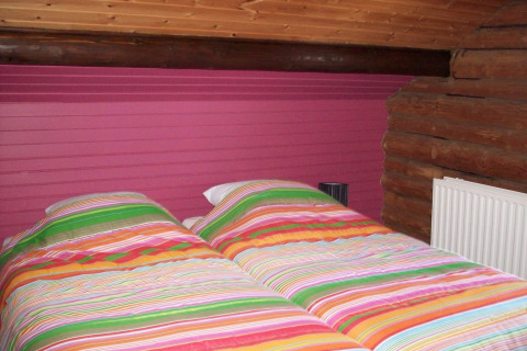 Buntes Schlafzimmer im Chalet Les Muguets, Belgien, mit gestreifter Bettwäsche und Holzelementen.
