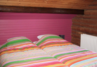 Buntes Schlafzimmer im Chalet Les Muguets, Belgien, mit gestreifter Bettwäsche und Holzelementen.