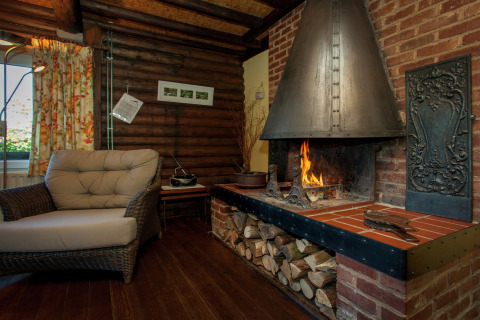 Gemütliches Chalet Les Muguets in Belgien mit Kamin, Sessel, Holzwänden und Holzlager.