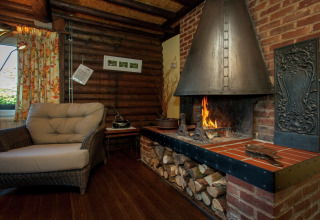 Gemütliches Chalet Les Muguets in Belgien mit Kamin, Sessel, Holzwänden und Holzlager.