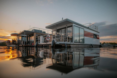 Houseboat moderno a Zehdenick sull’acqua calma al tramonto, con splendidi riflessi e atmosfera serena.