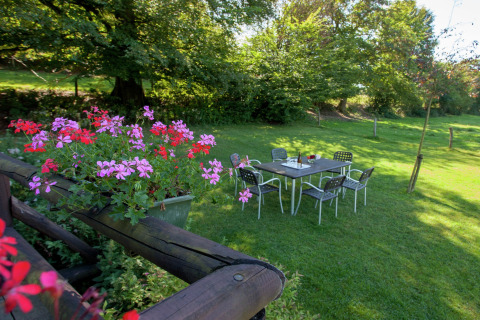Blumen im Vordergrund und ein Gartentisch auf einer Wiese beim Chalet ‘Les Muguets’ in Belgien.