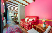 Area soggiorno del lodge Manonfa in Belgio con divano rosso, parete rosa e vista sulla sala da pranzo.