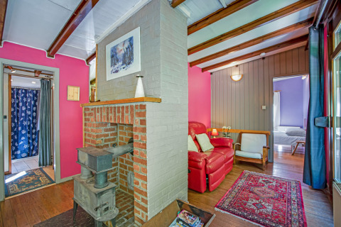 Zona living accogliente al lodge Manonfa in Belgio con stufa a legna e pareti colorate.