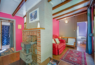 Zona living accogliente al lodge Manonfa in Belgio con stufa a legna e pareti colorate.