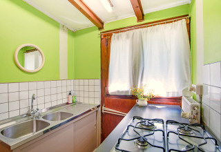 Lichte keuken van Manonfa-lodge in België met groene muren, gasfornuis, dubbele spoelbak en raam.