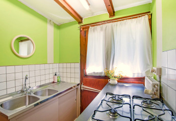 Cucina luminosa del lodge Manonfa in Belgio con pareti verdi, fornello a gas, doppio lavello e finestra.