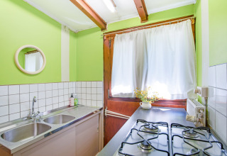 Cucina luminosa del lodge Manonfa in Belgio con pareti verdi, fornello a gas, doppio lavello e finestra.