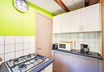 Colorata cucina al lodge Manonfa in Belgio con fornello a gas, microonde, macchina da caffè e orologio a muro.