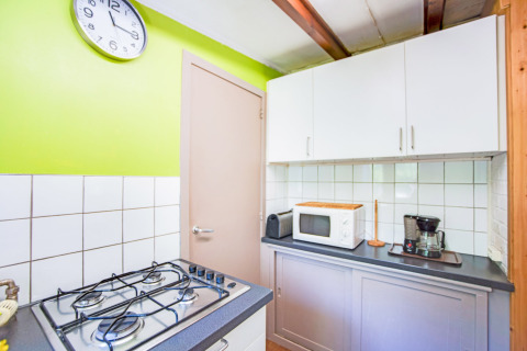 Colorata cucina al lodge Manonfa in Belgio con fornello a gas, microonde, macchina da caffè e orologio a muro.