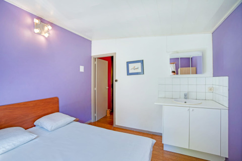 Camera luminosa al lodge Manonfa in Belgio con pareti viola, letto matrimoniale e lavandino.