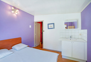 Camera luminosa al lodge Manonfa in Belgio con pareti viola, letto matrimoniale e lavandino.