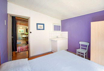 Stanza luminosa con pareti viola, lavandino, sedia e vista sulla sala da pranzo nel lodge Manonfa in Belgio.