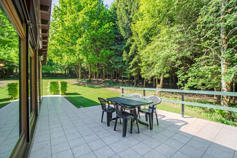 Terrazza esterna con tavolo e sedie, circondata da foresta presso il lodge Manonfa in Belgio.